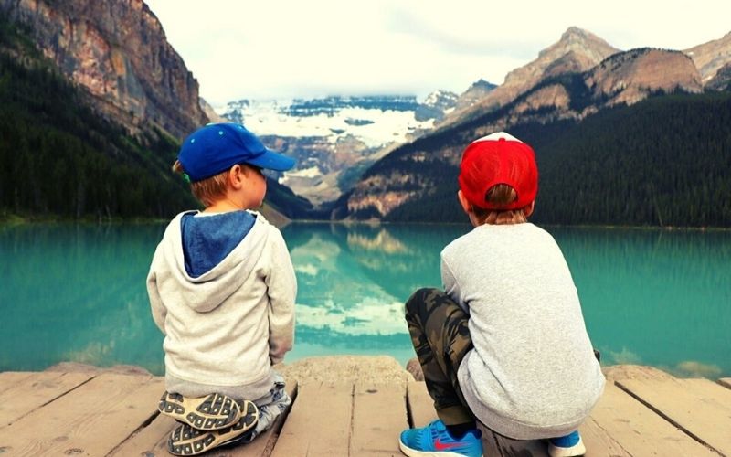 Two boys sitting looking at Lake Louise in Banff National Park.