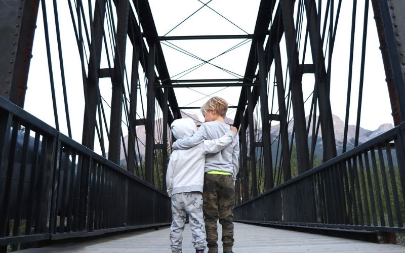 Two kids standing on the Canmore Old Railway Bridge in Canmore.