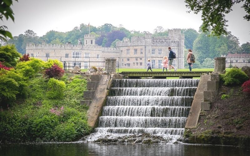 Family walking past running water during Leeds Castle half term activities.