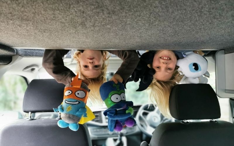 Kids playing in the pop top roof in a campervan.