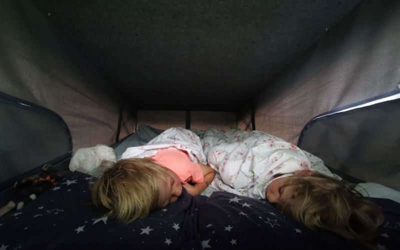 Kids sleeping up in the pop top roof of a campervan.