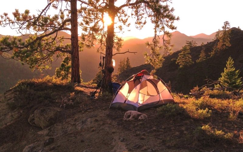 Sun rising over the mountains with tent in foreground