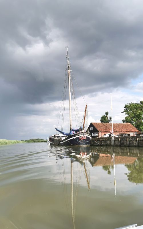 Barge moored on the River Alde at Snape Maltings in Suffolk - one of the most unusual places to stay in Suffolk.