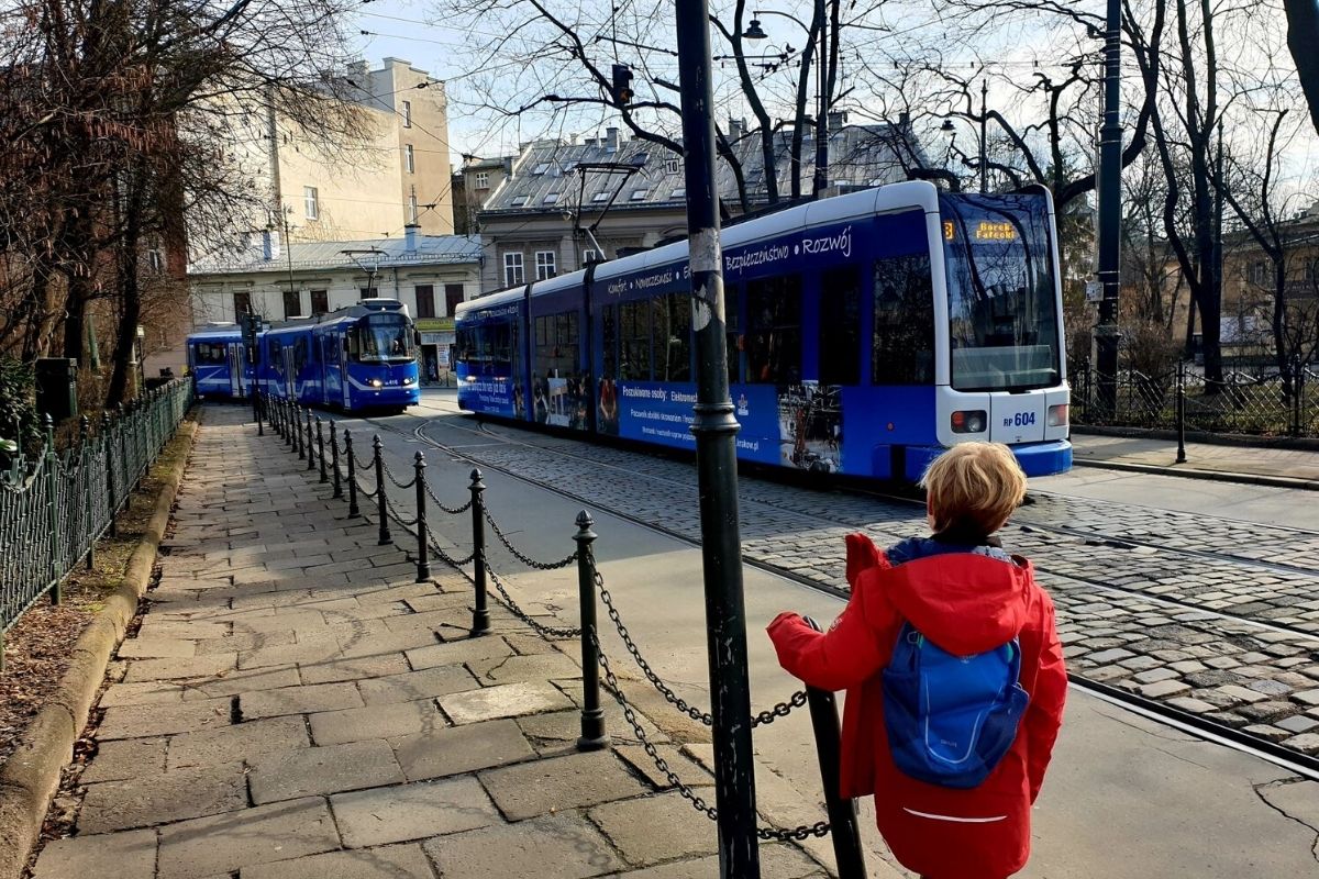 Boy in red jacket watching the trams in Krakow Poland.