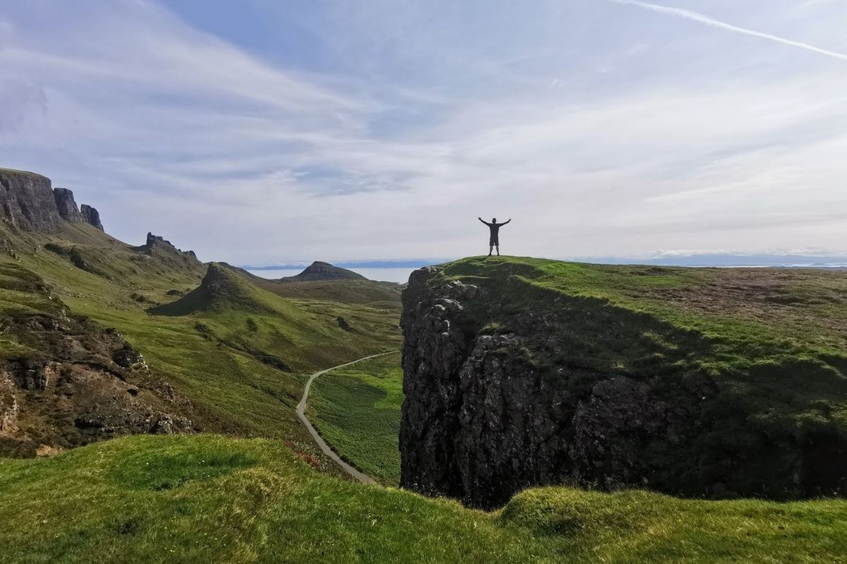 Man standing on the edge of a cliff in the dramatic landscape of The Quiraing on the Isle of Skye in Scotland