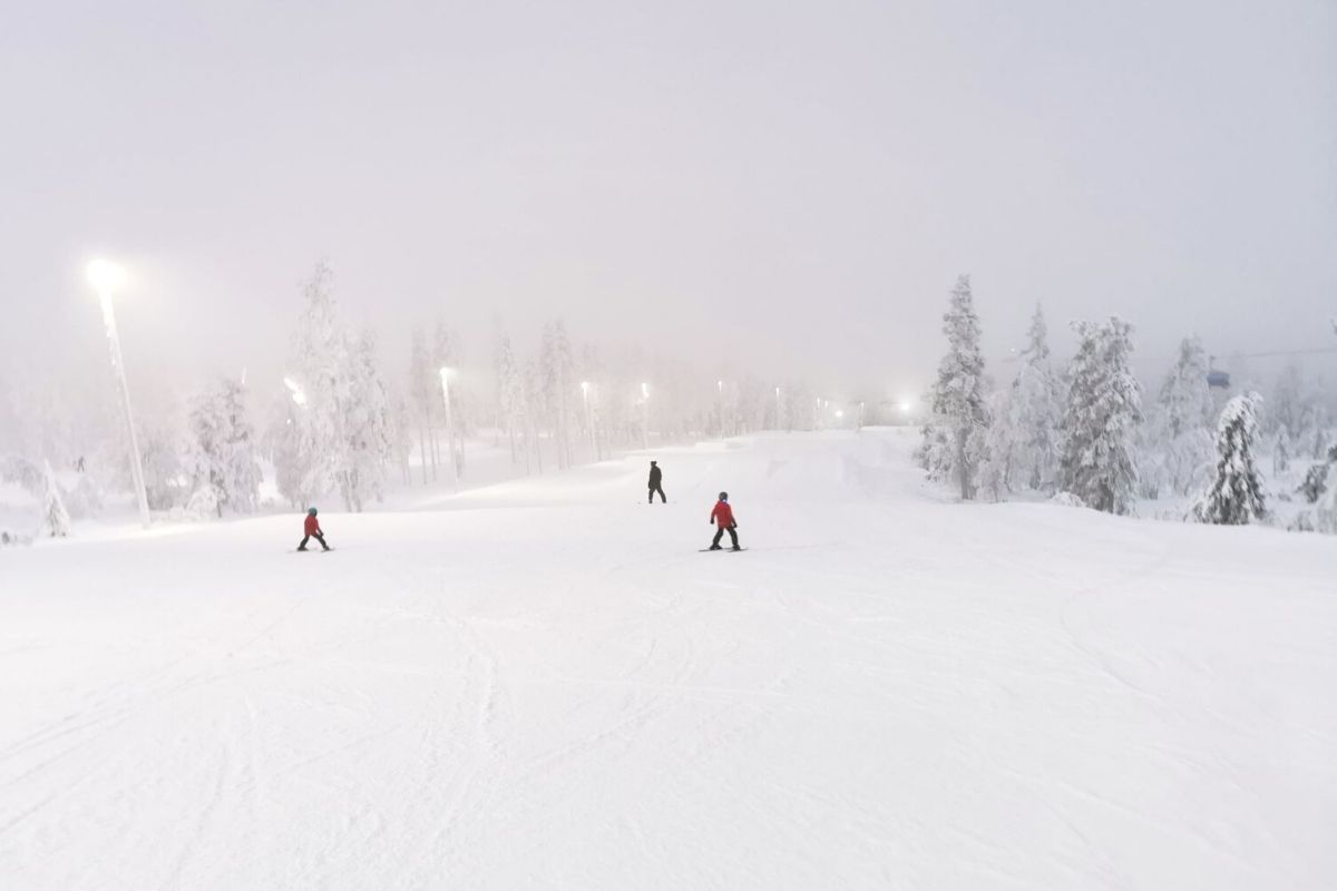 Three people on an empty ski slope in Levi Ski Resort in Lapland.