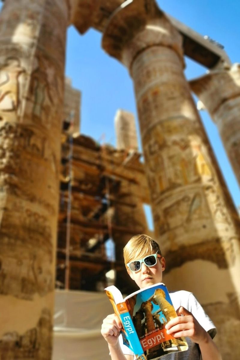 Kid reading the Egypt Rough Guide at Karnak Temple - one of the best things to do in Luxor with kids.