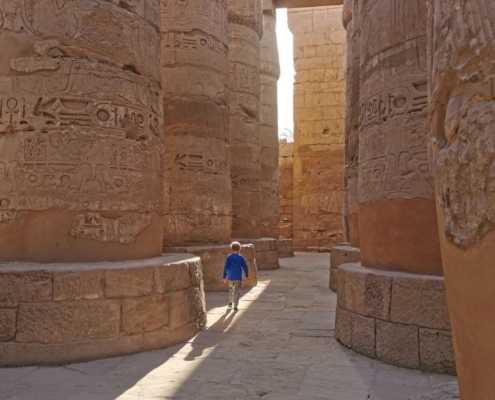 Small boy wandering through the columns at Karnak Temple in Luxor at sunrise