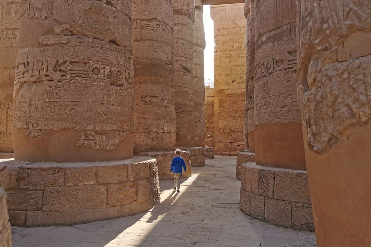 Small boy wandering through the columns at Karnak Temple in Luxor at sunrise