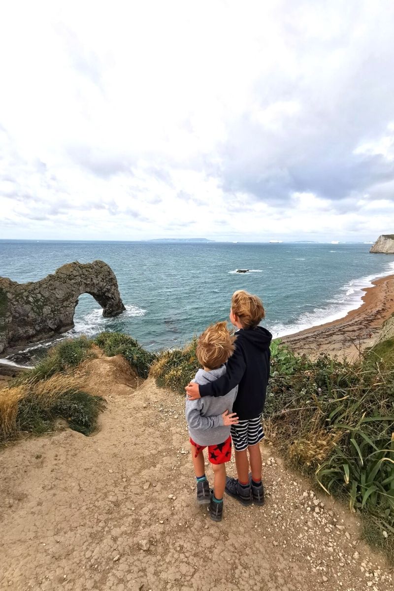 Two boys look at the view of Durdle Door and Durdle Door beach.