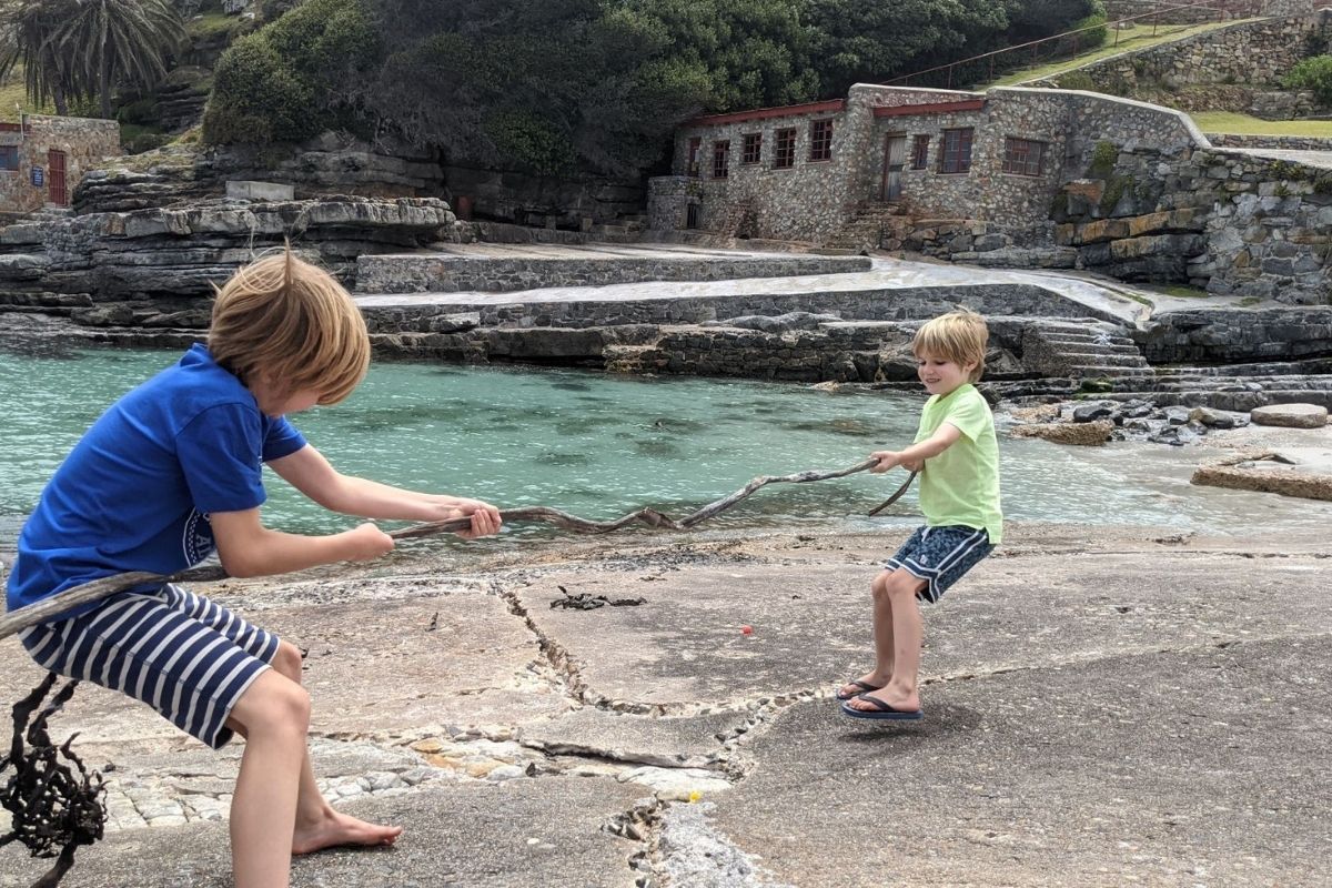 Two boys playing tug of war at the Old Harbour in Hermanus.