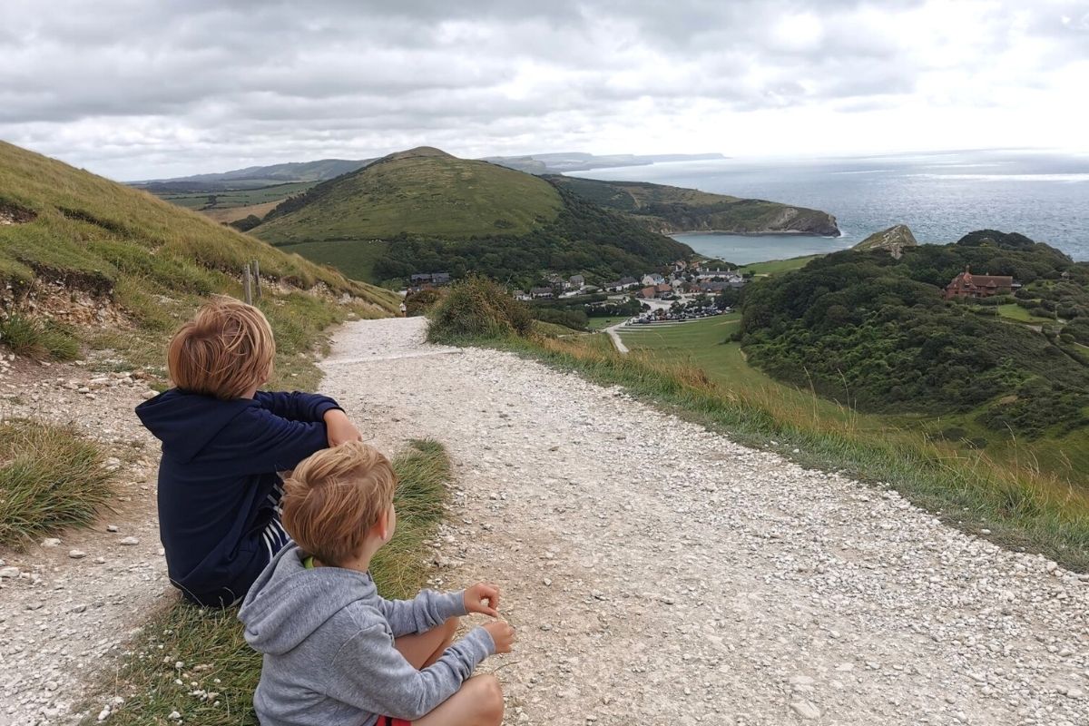 Two boys sitting on the coastal path from Durdle Door to Lulworth Cove..