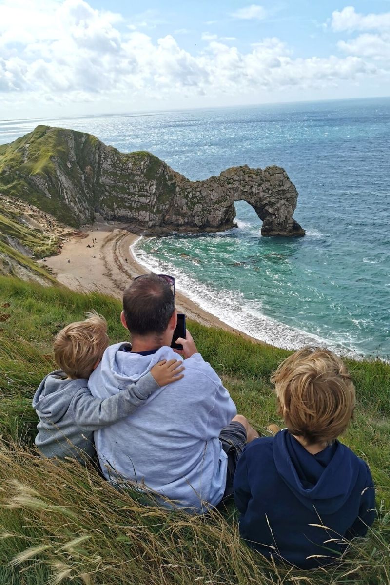 family taking in the views of Durdle Door beach in Dorset from the South West Coast Path.