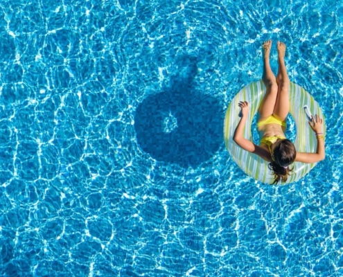 Aerial view of a lady sitting on an inflatable ring in the swimming pool.