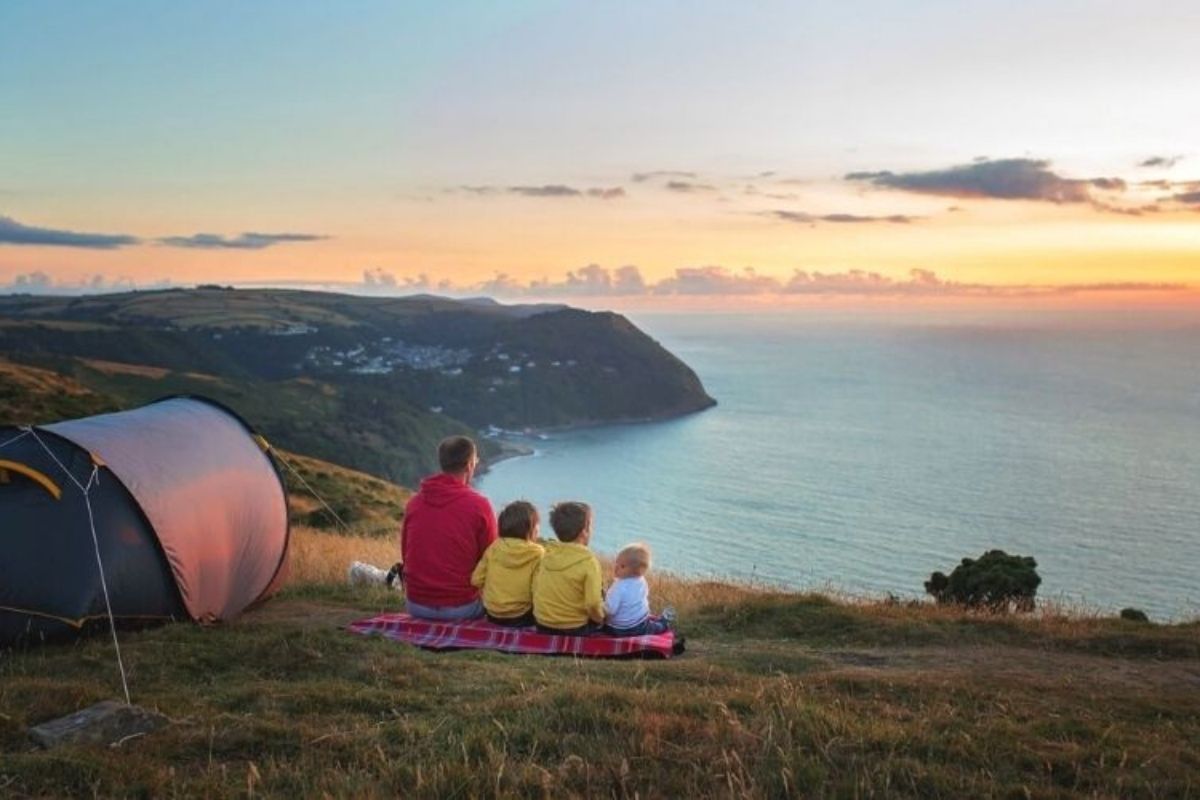 Family camping on the coast watching the sun set.