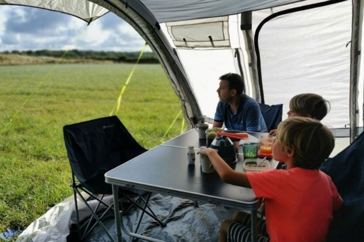 Family sitting in the living room area of the Olpro Cocoon Breeze air awning.