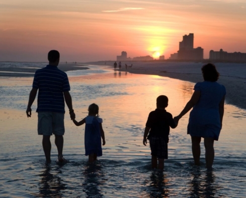 Family walking along a Florida beach at sunset.