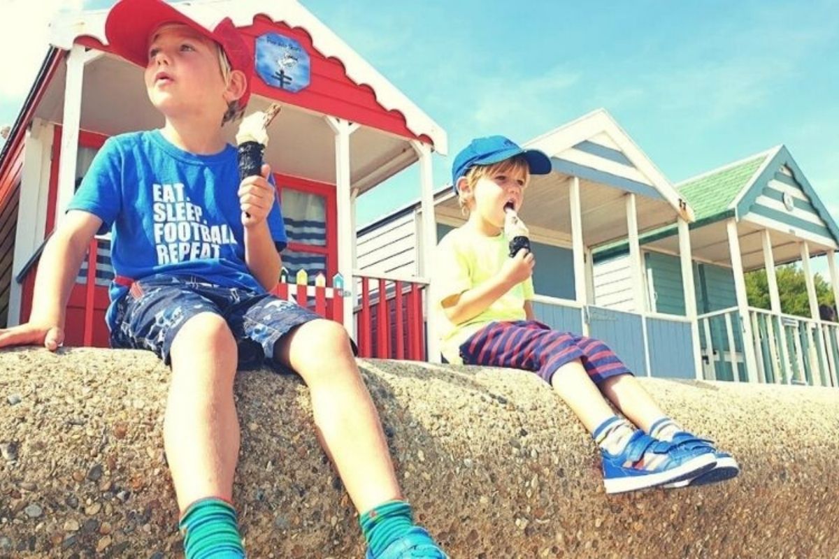 Two boys eating ice creams in front of the beach huts in Southwold in Suffolk.