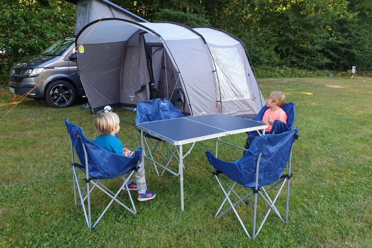 Two boys sitting in chairs on a campsite.