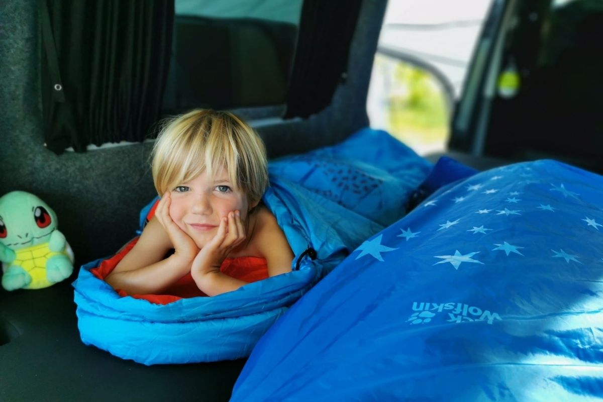 Young boy in a Jack Wolfskin sleeping bag while camping.