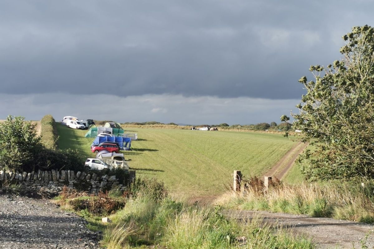 top camping tips for beginners is not to pitch your tent on a slope like the tents in this field.