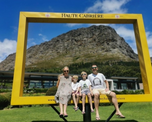 Family sitting in a large yellow frame at Haute Cabriere wine estate in Franschhoek in South Africa.
