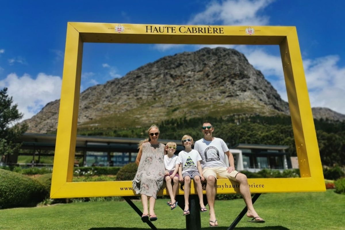 Family sitting in a large yellow frame at Haute Cabriere wine estate in Franschhoek in South Africa.