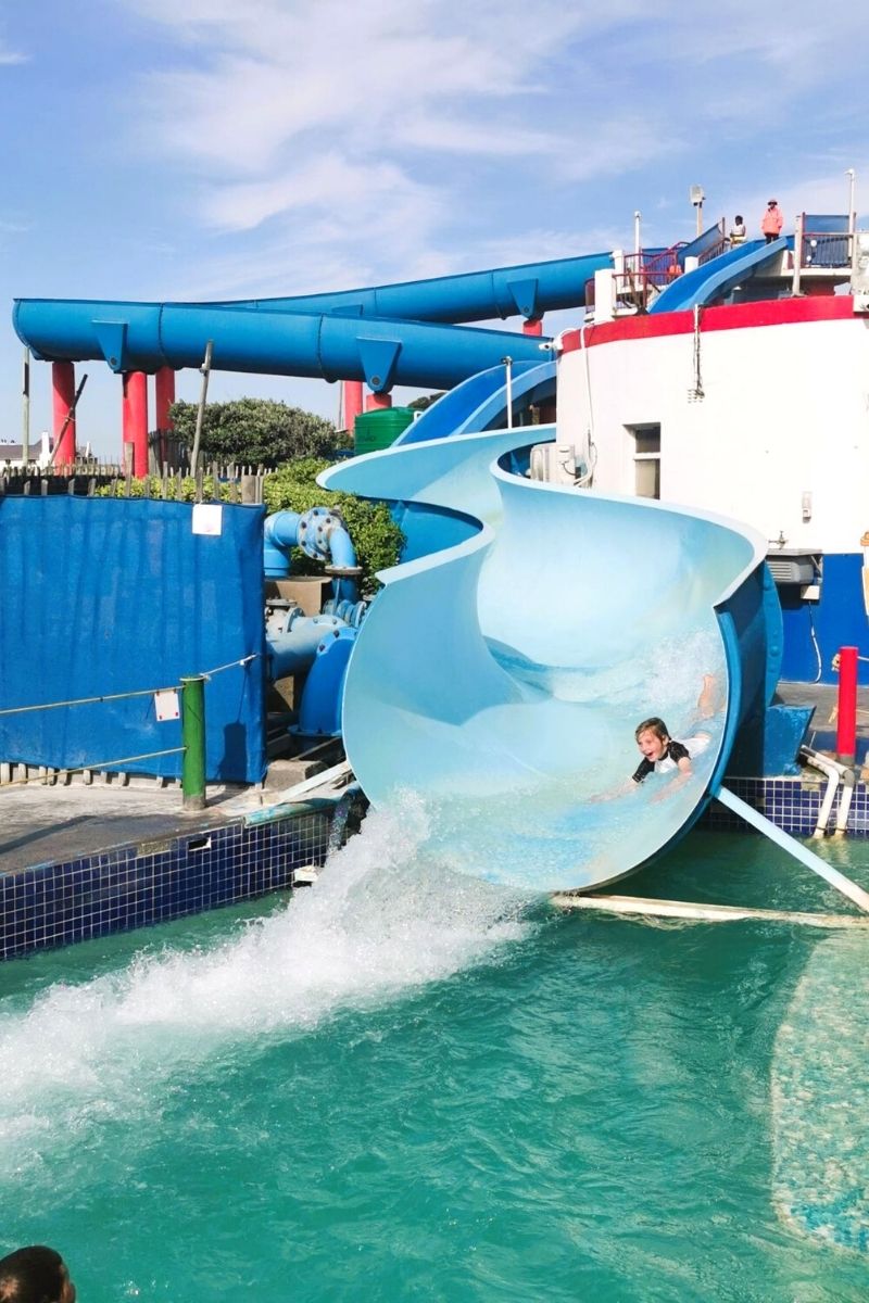 Kid sliding down the water slides at Muizenberg Beach in South Africa.