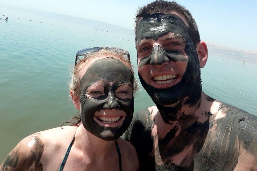 A couple covered in Dead Sea mud after a Dead Sea swimming experience in Jordan.