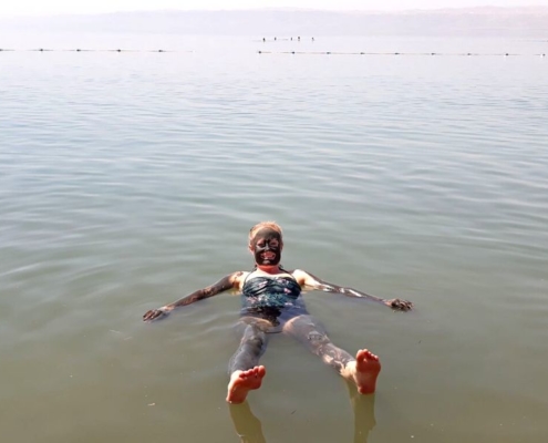 Lady covered in mud swimming in the Dead Sea in Jordan.