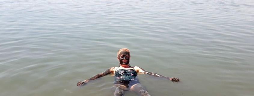 Lady covered in mud swimming in the Dead Sea in Jordan.