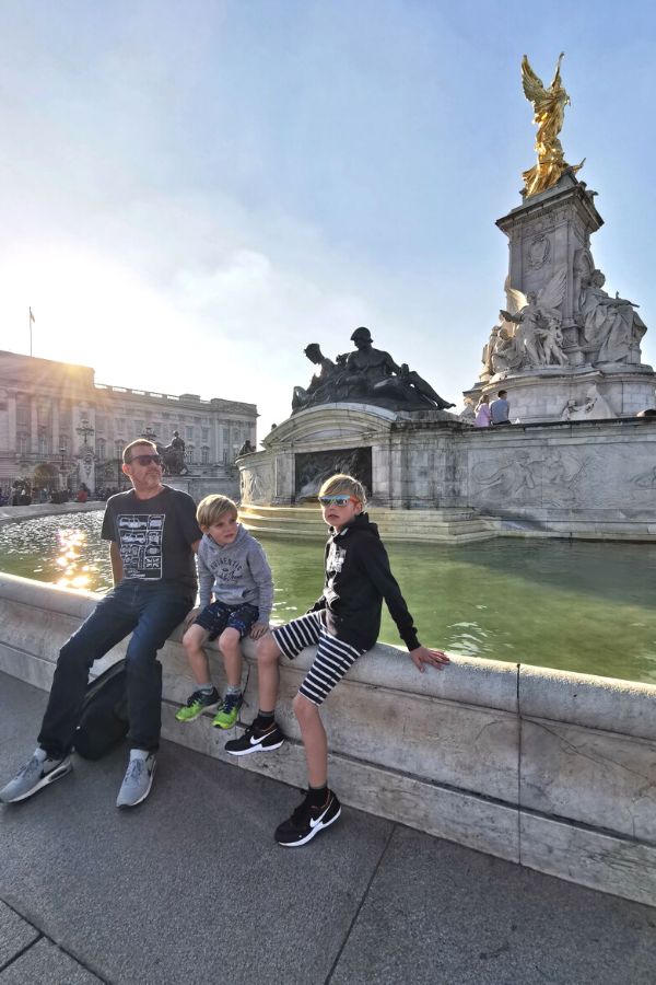 Family sitting by the fountain outside Buckingham Palace in London.