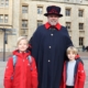 Two boys in red coats standing either side of a Yeoman at the Tower of London - one of the most visited attractions in London with kids.