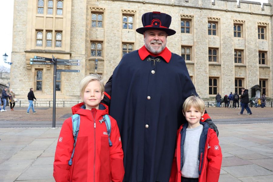 Two boys in red coats standing either side of a Yeoman at the Tower of London - one of the most visited attractions in London with kids.