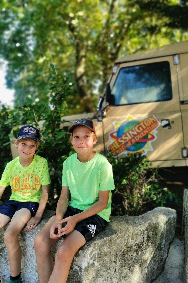 Two boys sitting in front of a Chessington safari jeep.at one of the best attractions for kids near London.