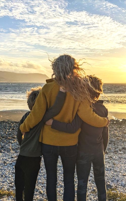 Mum and two boys watching sunset at West Shore Beach in Llandudno in North Wales.