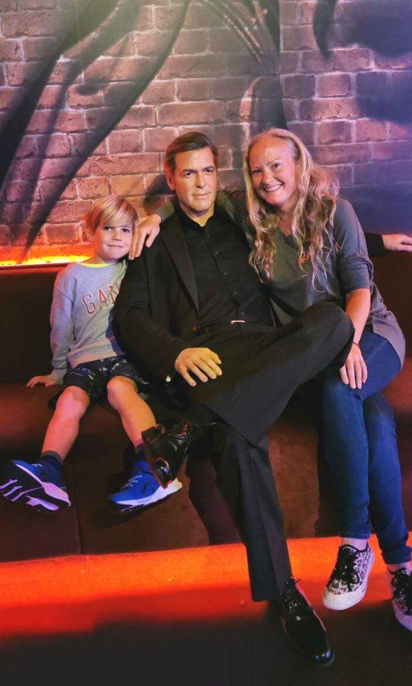 Mother and son sitting next to George Clooney at Madame Tussauds in London.
