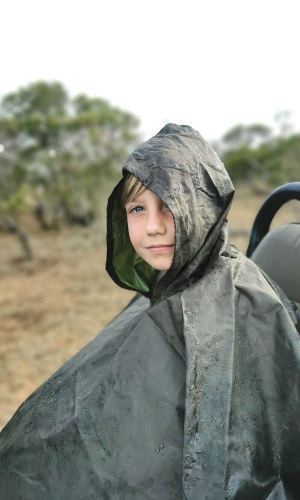 Young boy on safari in the rain wearing a waterproof poncho.