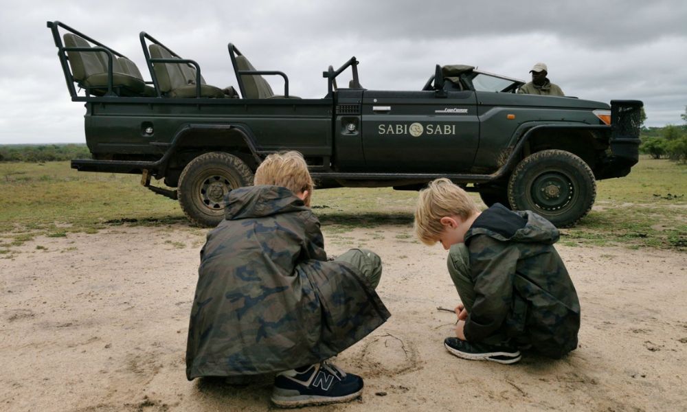 Boys playing in the sand in front of a safari vehicle at Sabi Sabi Game Reserve in South Africa.
