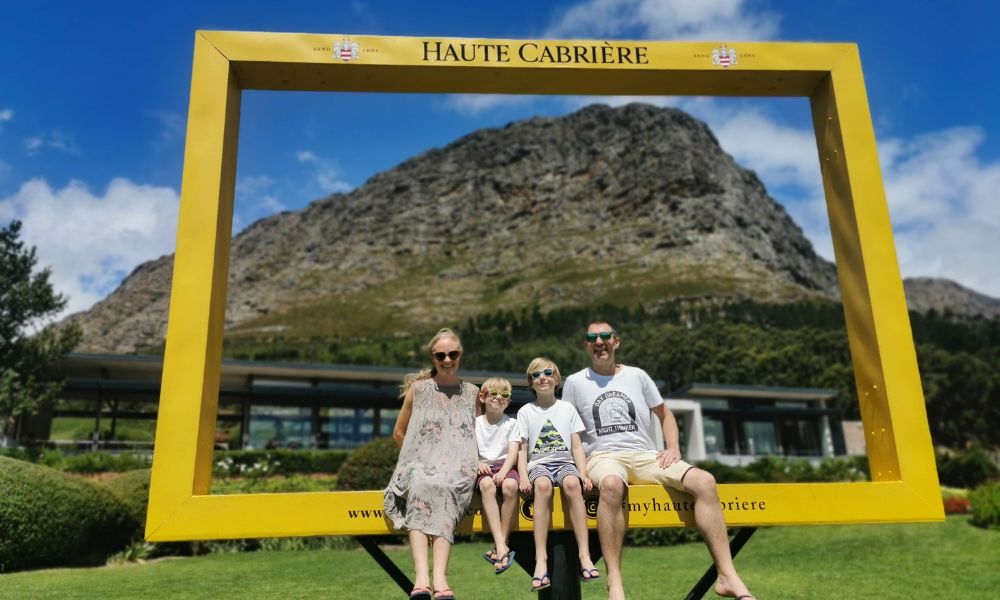 Family sitting in a giant yellow frame at the Haute Cabriere wine estate in the Cape Winelands in South Africa.