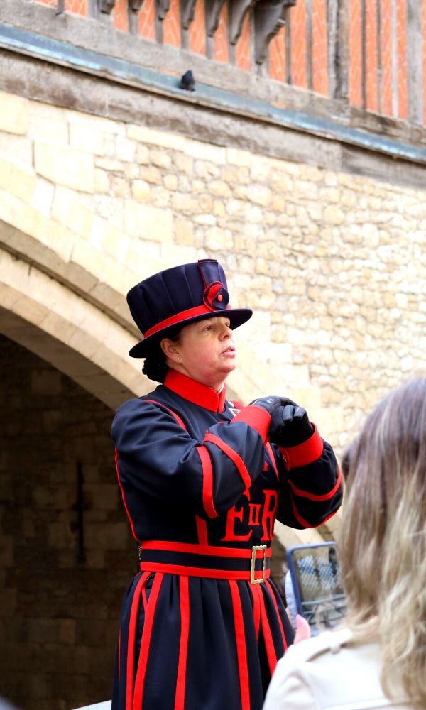 A female Yeoman Warder giving a tour of the Tower of London.