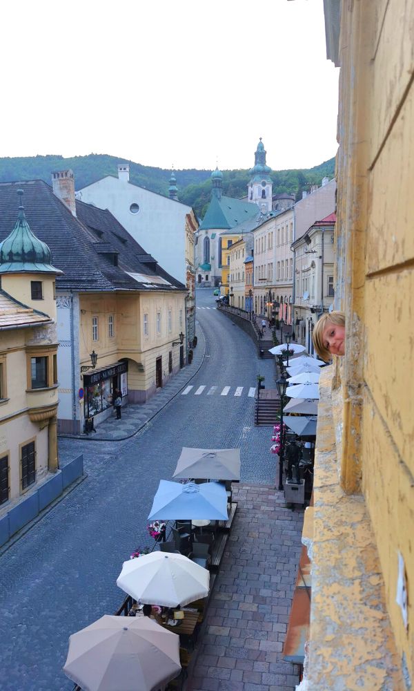 Boy looking out of the window of his apartment in Banksa Stiavnica in Slovakia in early evening with empty streets below.