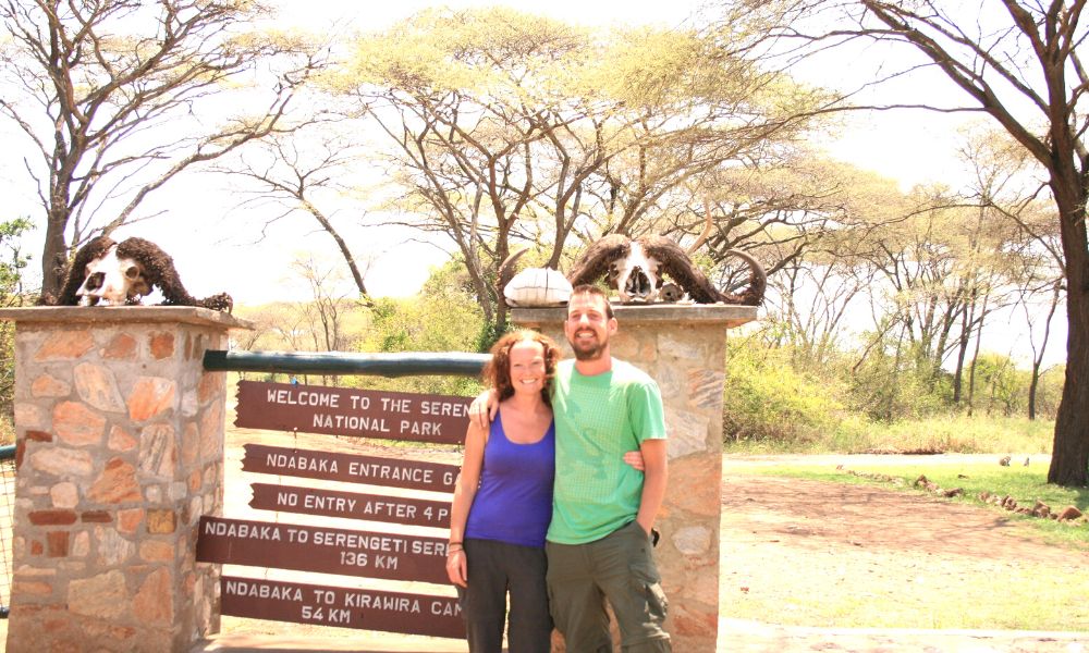 Couple standing next to the entrance to the Serengeti National Park in Tanzania - one of the best safari destinations in Africa.