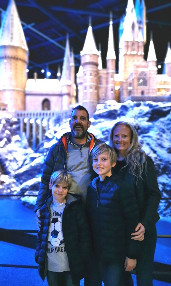 Family of four standing in front of Hogwarts in the Snow at the WB Studio Tour.