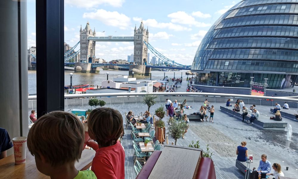 Kids eating in Five Guys at Tower Bridge with views of the splash park and Tower Bridge.