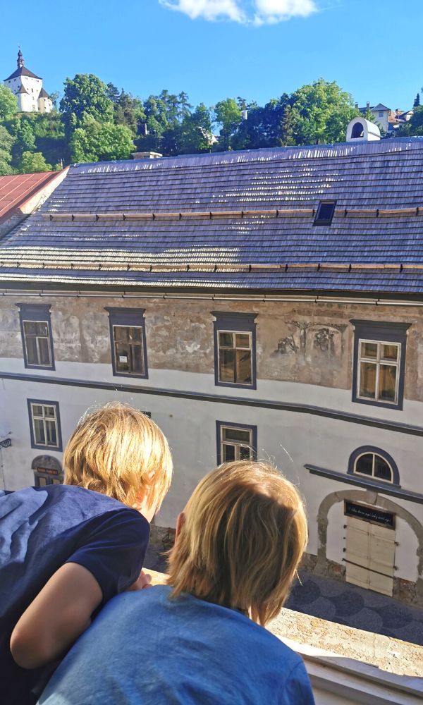 Kids enjoying the view out of a window of an apartment in the centre of Banska Stiavnica in Slovakia.