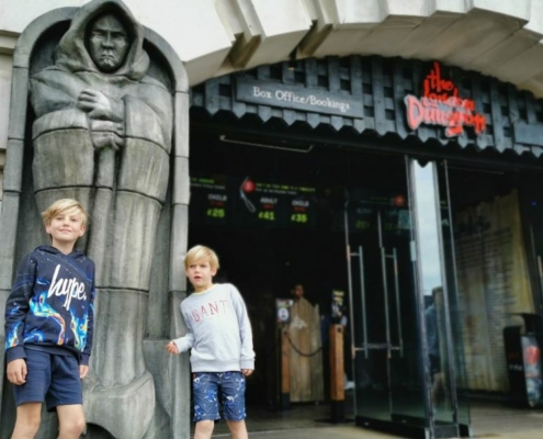 Two little boys standing outside the front of the London Dungeons. - one of the best things to do at Halloween in London for kids.
