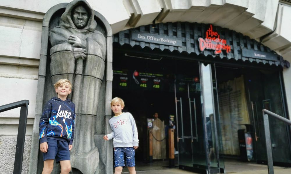 Two little boys standing outside the front of the London Dungeons. - one of the best things to do at Halloween in London for kids.