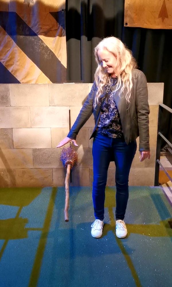 Woman standing looking down at a broomstick at Harry Potter Studio Tour in London.