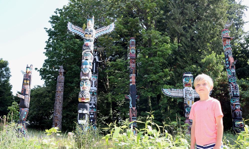 Young boy standing in front of the totem poles in Vancouver.